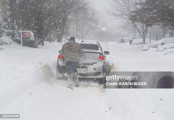 Man tries to push a car stuck in the snow, January 23, 2016 in Prince William County, Virginia. A deadly blizzard with bone-chilling winds and...