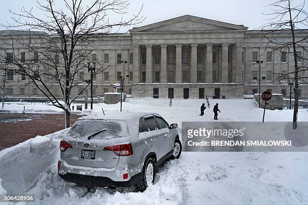 People cross a snow covered street near the Smithsonian's National Portrait Gallery after a snowstorm January 23, 2016 in Washington, DC. A deadly...