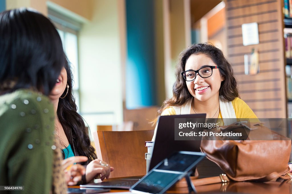Hipster sorridente hispânico Menina de colégio enquanto se encontram a estudar no grupo de estudo