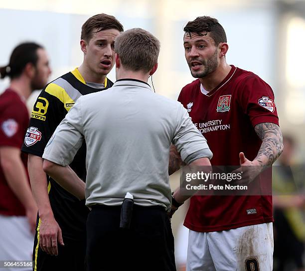 Marc Richards of Northampton Town and Andy Fleming of Morecambe look on as referee Gavin Ward makes a point during the Sky Bet League Two match...