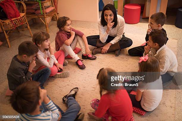 preschool insegnante giocando giochi con gruppo di bambini. - bambini seduti in cerchio foto e immagini stock