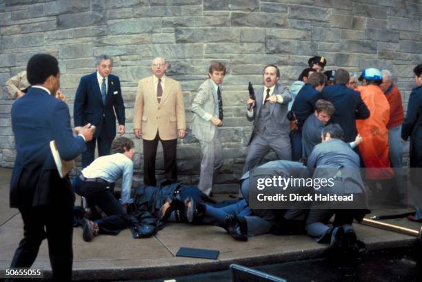 View of armed Secret Service agents around the bodies of policeman Thomas K Delahanty and White House Press Secretary James Brady outside the...