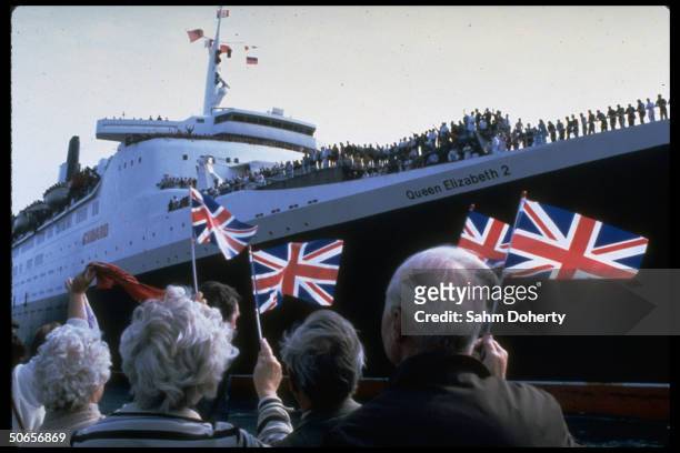 Wellwishers waving British flags as they bid farewell to troops sailing on QE2 as it departs for Falkland Isands