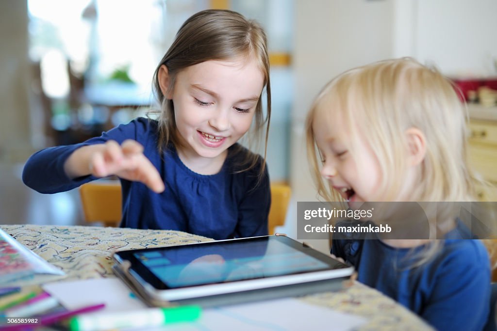 Zwei kleine Schwestern spielen mit einem Digitaltablett