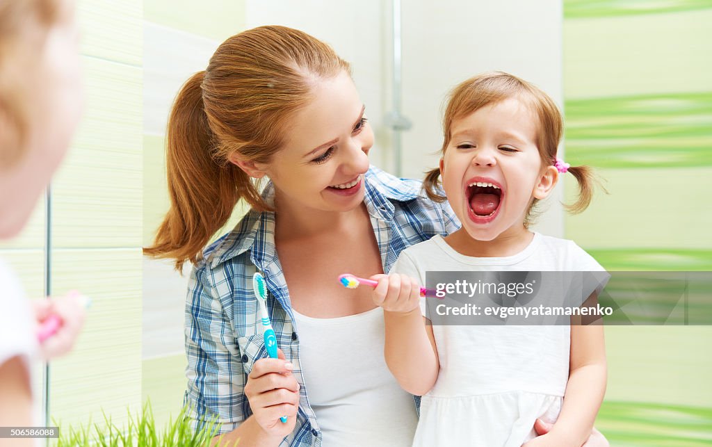 Happy family mother and child girl cleans teeth with toothbrush