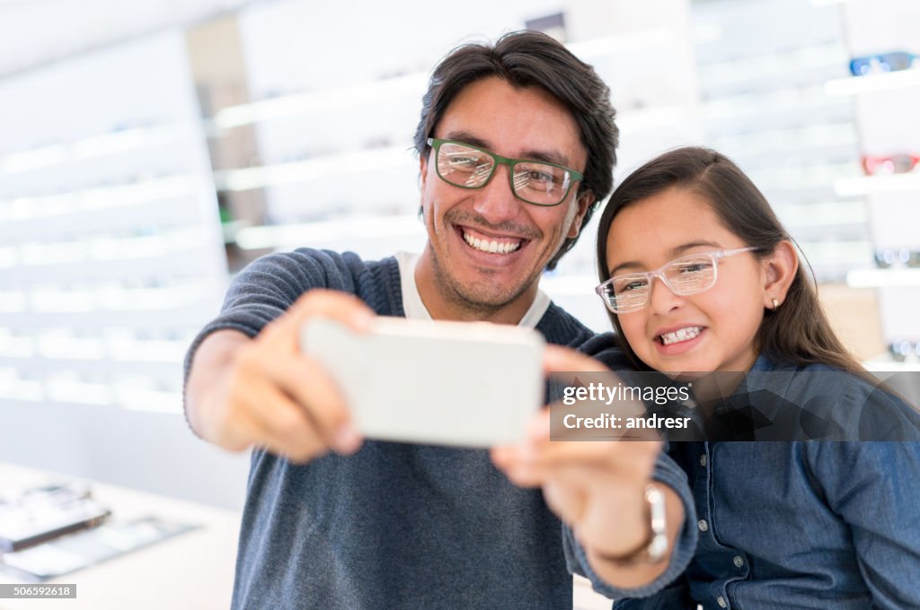 Padre e hija tomándose una selfie con gafas en óptica