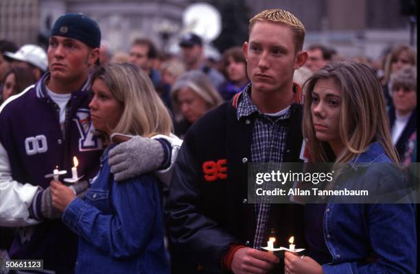 Somber Columbine High School student athletes hugging their girlfriends during candleight vigil for 12 students & 1 teacher killed in suicide...