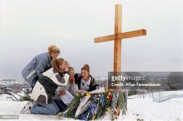 Grieving Columbine High School students mourning at cross marked memorial in days after 12 students & 1 teacher were killed by troubled seniors Eric...