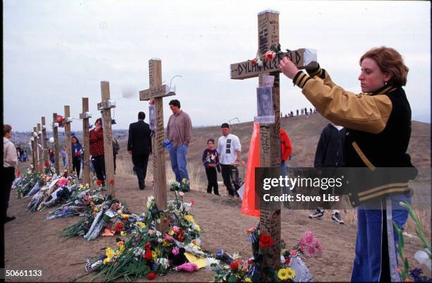 Person putting flowers on memorial cross for Dylan Klebold, who w. Friend Eric Harris went on shooting spree at Columbine High School, killing 13 &...