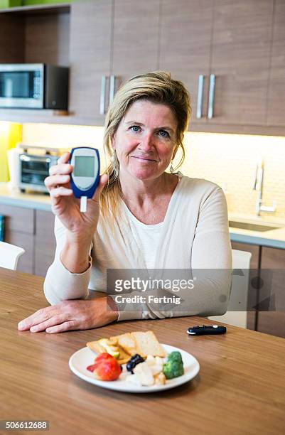 diabetic woman holds up a glaucometer - glaucometer stockfoto's en -beelden