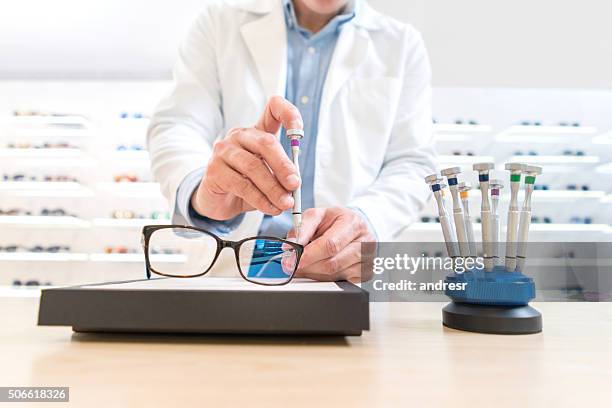 man repairing glasses at the optics - eyeglass repair stock pictures, royalty-free photos & images