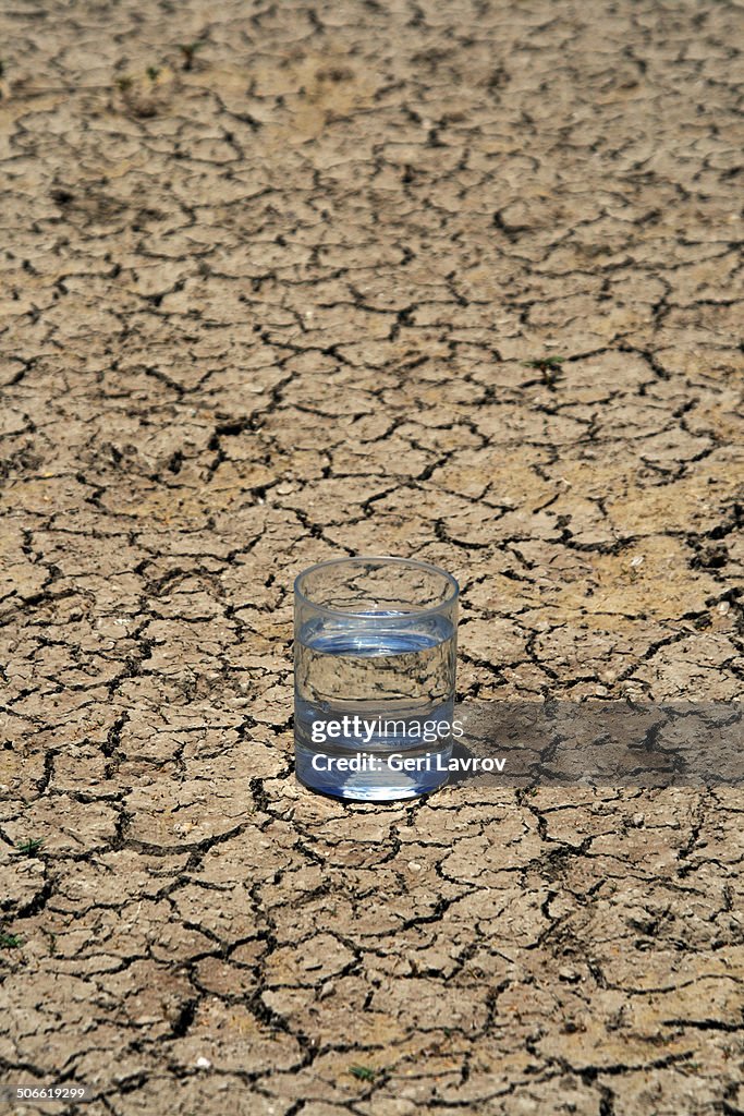 Glass of water on parched dry soil