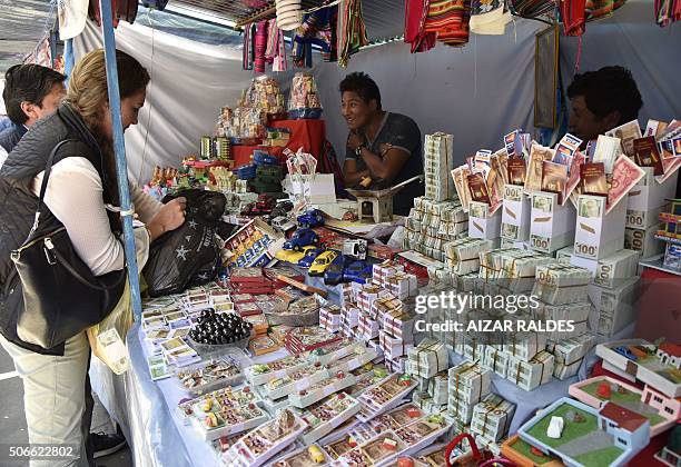 Man sells a number of miniature goods and fake 100-dollar bills at the start of the Alasitas festival on January 24 , 2016 in La Paz. The month-long...