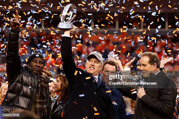 General Manager and Executive Vice President of Football Operation for the Denver Broncos John Elway holds up the Lamar Hunt Trophy with former...