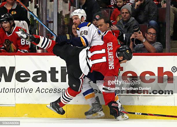 Andrew Desjardins of the Chicago Blackhawks gets dumped to the ice by Kyle Brodziak of the St. Louis Blues at the United Center on January 24, 2016...
