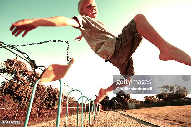 boy jumping off a swing - stunt person 個照片及圖片檔