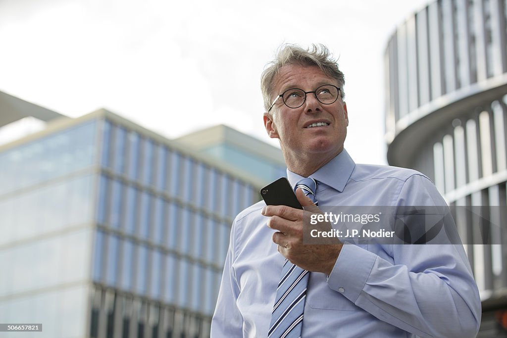 Businessman with phone in front of office