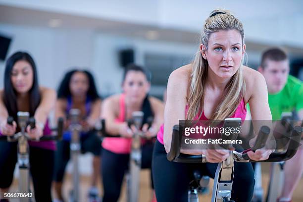 cycling together in exercise class - spin instructor stock pictures, royalty-free photos & images