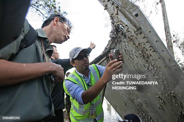 Malaysian official takes pictures of a piece of suspected aircraft debris after it was found by fishermen on January 23, at a beach in the southern...