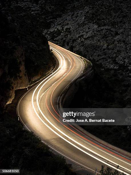 it curls in the shape of s with the lights and stelas of the vehicles in movement - long exposure light trails stock pictures, royalty-free photos & images