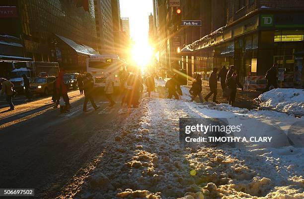 People walk past a large bank of snow on Park Avenue January 25, 2016 as New Yorkers return to work after the city was hit with a record-setting...