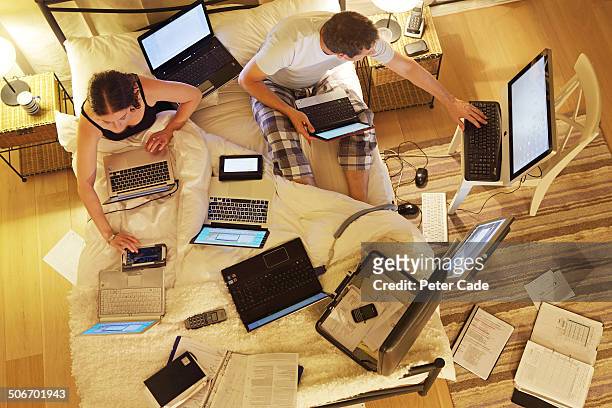 couple in bed surrounded by computers - large group of objects stock pictures, royalty-free photos & images
