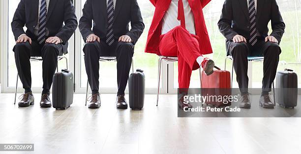 four men on chairs, three black one red suit - individuality foto e immagini stock