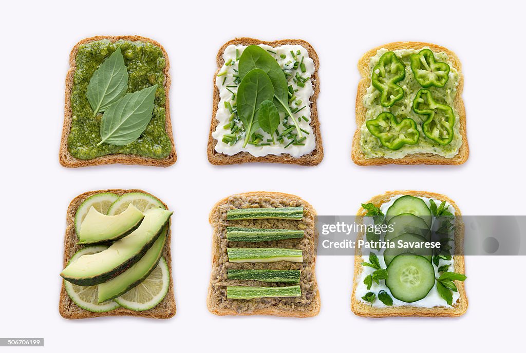 Toast of green vegetables in a row on white backgr