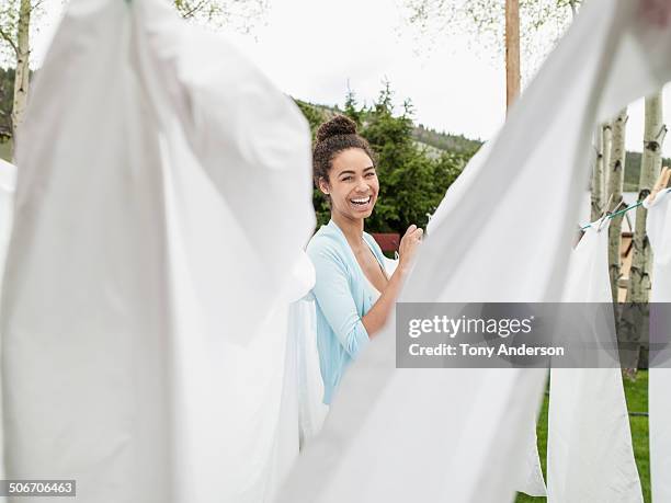 young woman hanging the laundry outdoors - white laundry foto e immagini stock