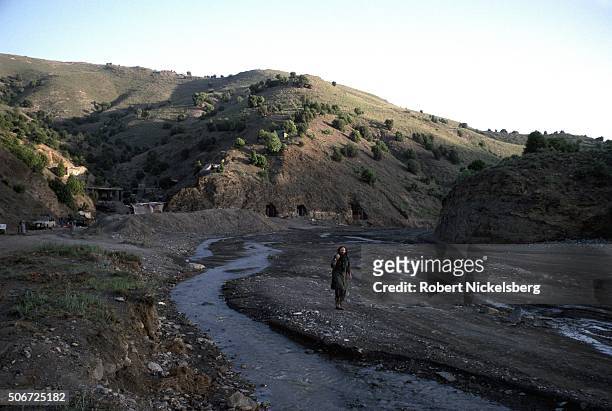 Associated Press reporter and stringer Patrick O'Donnell walks up a riverbed outside of the Zhawar training camp built and controlled by Afghan...