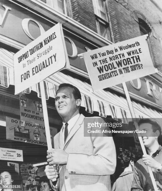 Musician and actor Harry Belafonte and protesters holding signs and marching during a protest against segregation by Woolworths department stores,...