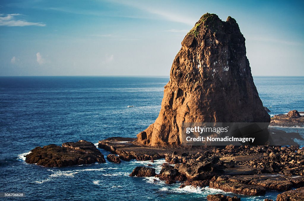Huge Tanjung Papuma rock with boats in the sea