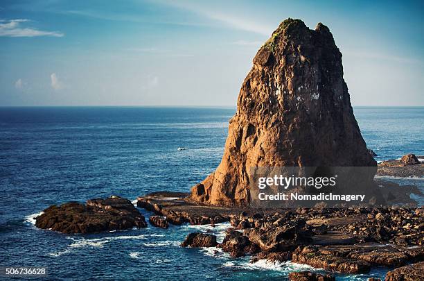 huge tanjung papuma rock with boats in the sea - large rock stock pictures, royalty-free photos & images