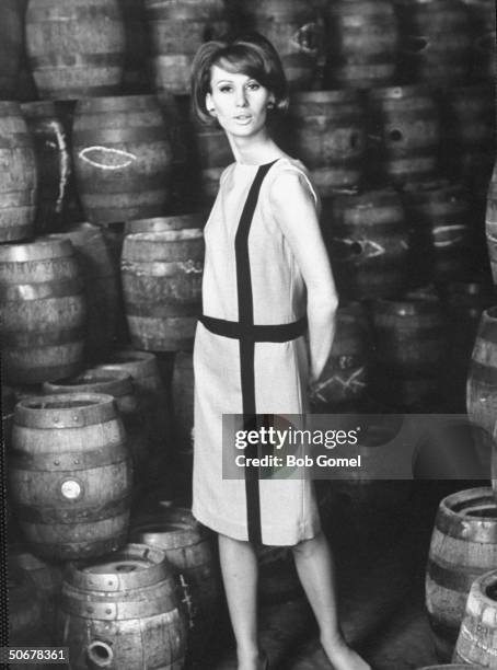 European model Brigitte Bauer, wearing cotton summer shift in warehouse full of barrels.