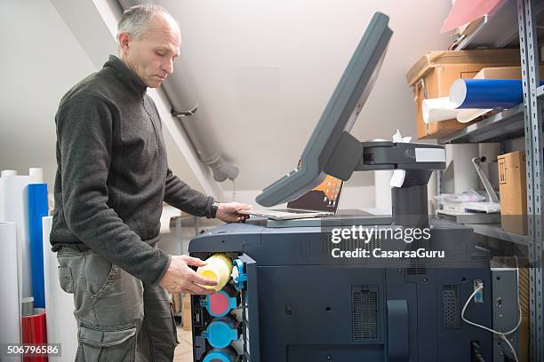 man changing printer cartridge - large format printer stock pictures, royalty-free photos & images
