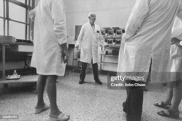 Head of Institute of Exprimmental Research and Surgery Dr. Hans Selye talking to unidentified people in a laboratory during an experiment.