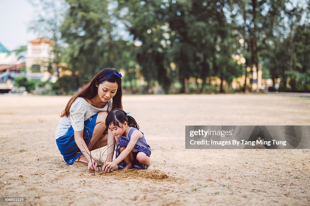 Mom & child putting up twigs on beach joyfully