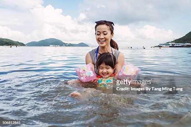 Mom teaching toddler to swim in the sea