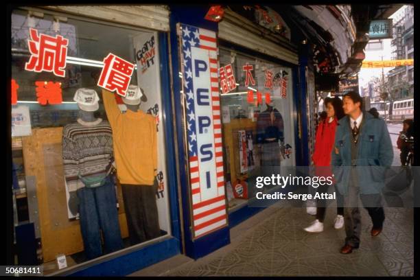 Pedestrians passing Pepsi store.