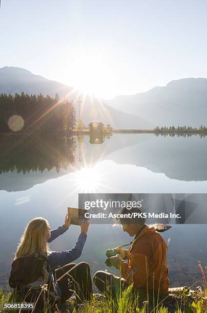 hiking couple take photo with tablet & dslr camera - sun flare couple stockfoto's en -beelden