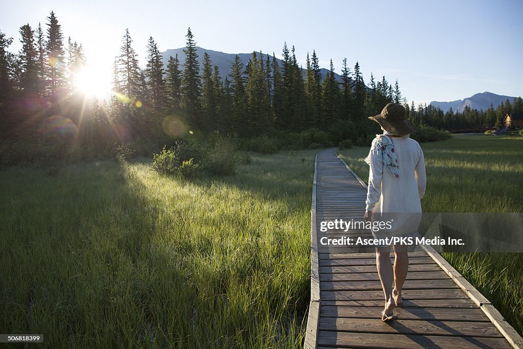 Woman walks along mountain boardwalk, sunrise