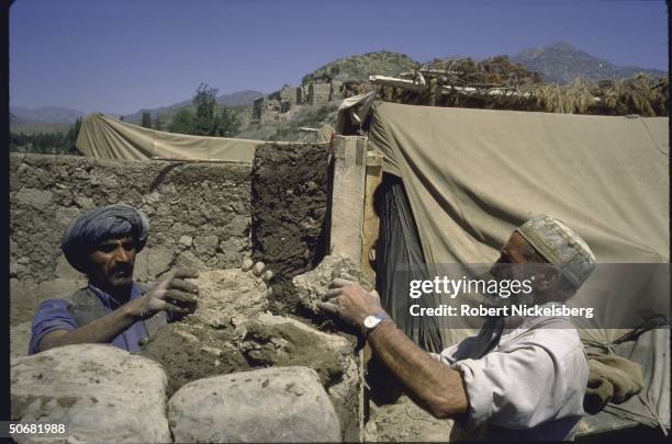 Mujahideen rebels building houses with Soviet ammo cases that are found along the road.