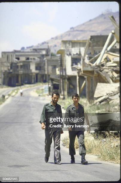Ruined Golan Heights Village, Quneitra, ghost town on Syrian-Israeli Demarcation Line. 2 Syrian Soldiers walking down the street.