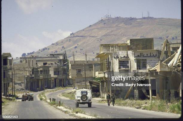 Ruined Golan Heights village, Quneitra, ghost town on Syrian-Israeli Demarcation Line. UN trucks, Arab And Syrian Soldiers walking with Spy Hill...