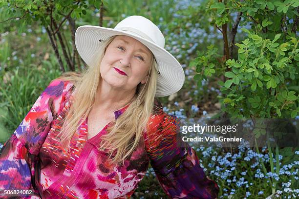 senior woman in colourful blouse relaxes in spring garden. - multi colored blouse stock pictures, royalty-free photos & images