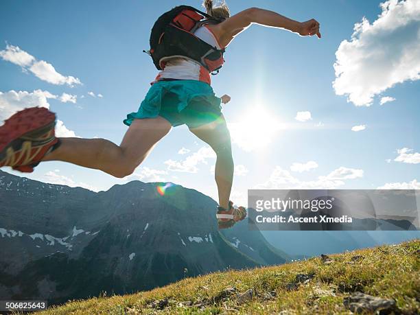 trail runner bounds along mountain ridge crest - trailrunning stock-fotos und bilder