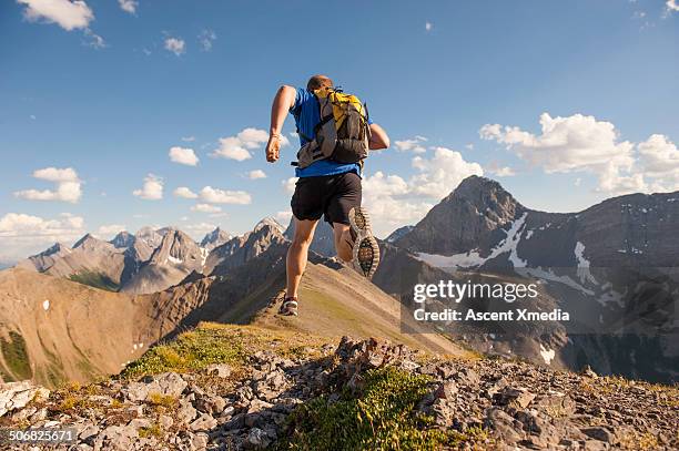 trail runner in mid air stride, on mountain ridge - trailrunning stock-fotos und bilder