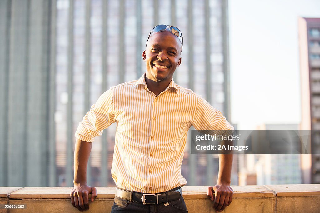 A portrait of a man standing on the balcony of his city apartment in Johannesburg, South Africa.