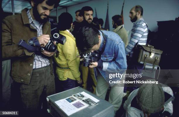 Press photographers taking pictures of photos on display during investigation into supposed death of infamous Nazi doctor Joseph Mengele, who cruelly...