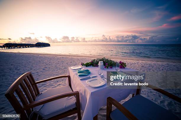 romantic dinner on the beach with sunset - beach pavilion stock pictures, royalty-free photos & images